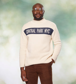 Man with one hand in his pocket, wearing a cream-colored "Central Park NYC" sweater 