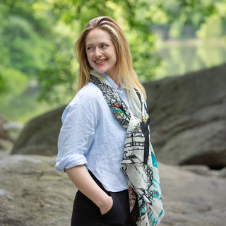 Woman wearing a colorful handpainted  scarf outdoors with greenery and stones in Central Park in the background