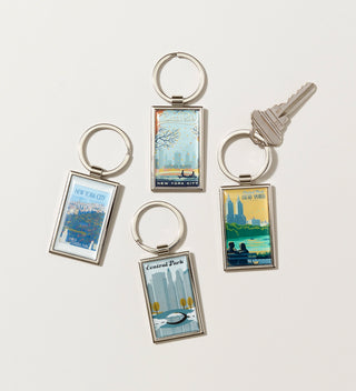 a group of key chains featuring Travel Poster style artwork with  various scenes in Central Park on a  grey background