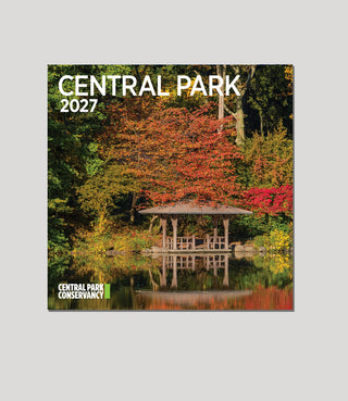 A square wall calendar cover for Central Park Conservancy 2027, featuring a scenic photograph of a wooden pavilion reflected in a lake surrounded by autumn trees in green, orange, and red. The text 'CENTRAL PARK 2027' appears at the top, and 'CENTRAL PARK CONSERVANCY' appears at the bottom left.