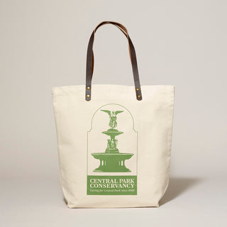 Natural canvas tote bag with green Central Park Conservancy Bethesda Fountain design with dark brown leather handles standing with  light gray background