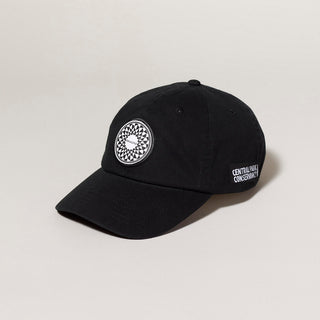 Black cap with a circular patch of hte Imagine mosaic from Strawberry Fields in Central Park on a light gray background