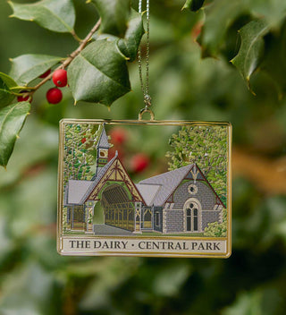 Intricate brass ornament featuring The Dairy Visitor Center and Gift Shop in Central Park, surrounded by trees and vibrant greenery. All products available through Central Park Conservancy Shop.