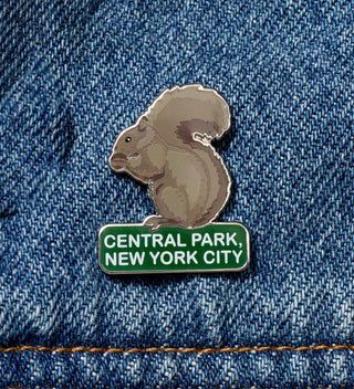 Close-up of an enamel pin featuring a squirrel and the text 'Central Park, New York City,' attached to a denim jacket.