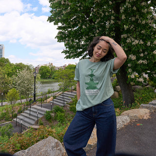 Person wearing a green t-shirt with a print of Bethesda Fountain, standing outdoors on the greeroof of the Davis Center in Central Park NYC. 